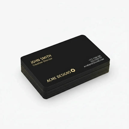 Stack of custom black business cards with gold text on a white background