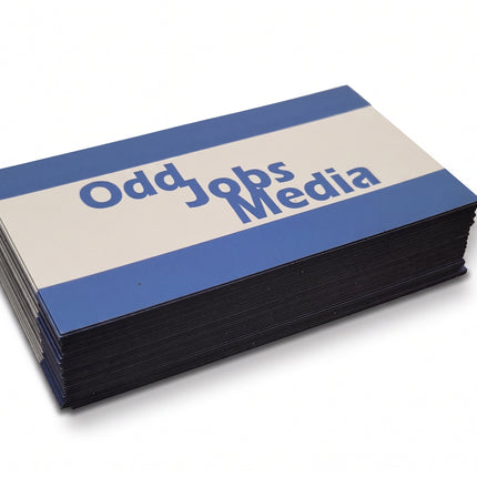 [photo] A stack of rectangular business card magnets with blue and white horizontal stripes and the text 'Odd Jobs Media' printed on a plain white background.