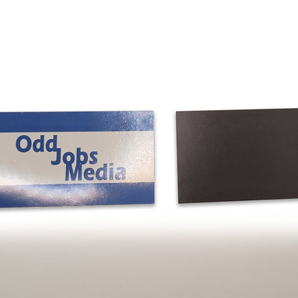 [photo] A rectangular magnet with the text 'Odd Jobs Media' in blue shown beside its plain black magnetic back on a plain white background.