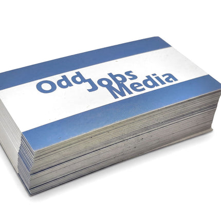 [photo] A stack of business cards with blue and white borders and the text 'Odd Jobs Media' printed on a pure white background.