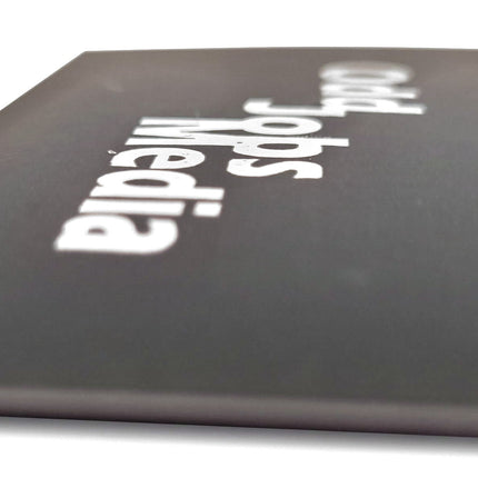 [photo] A close-up shot of a black business card with the words 'Odd Jobs Media' printed in white, photographed on a pure white background.