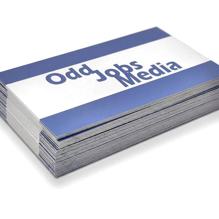 [photo] A stack of business cards with a blue and white design, featuring the text 'Odd Jobs Media' in blue, photographed on a pure white background.