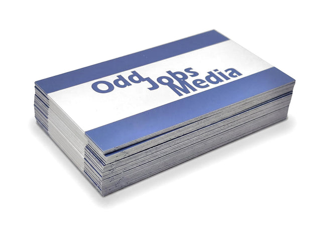 [photo] A stack of business cards with a blue and white design, featuring the text 'Odd Jobs Media' in blue, photographed on a pure white background.