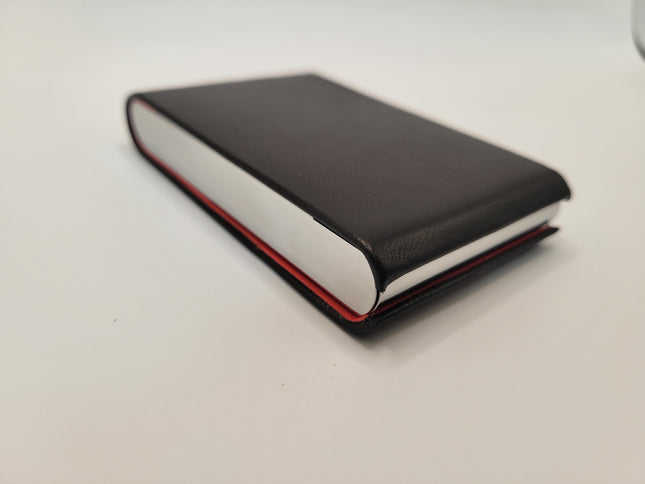 A slim leather business card holder with a black textured cover, metal silver sides, and a thin red interior accent, photographed on a plain light background.