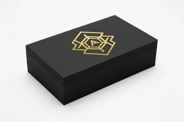 [AI] Stack of black business cards with metallic gold foil geometric design on thick stock